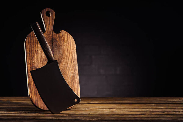 closeup view of wooden cutting board and butcher axe on table 
