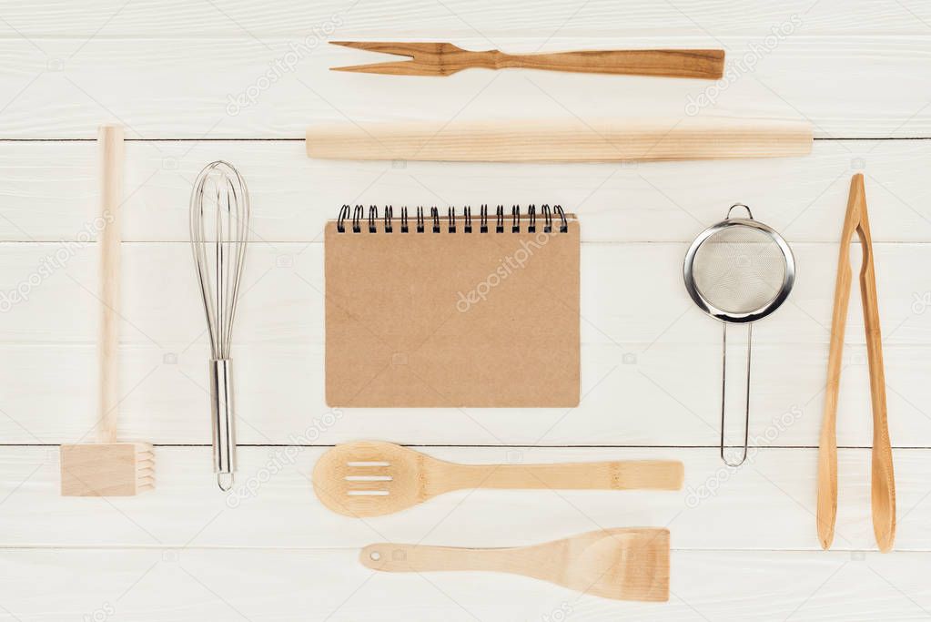 top view of textbook and kitchen utensils on wooden white table  