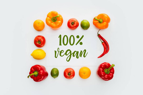 верхний вид рамки из овощей и фруктов с текстом 100% Vegan изолирован на белом

