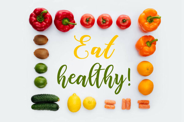 top view of frame with vegetables and fruits and text Eat Healthy isolated on white