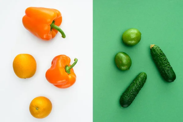 top view of orange and green fruits and vegetables on white and green surface