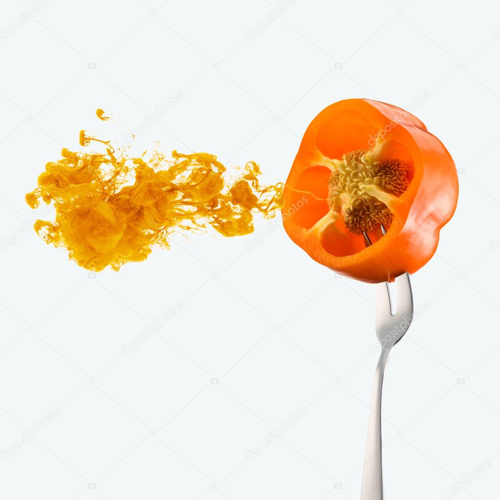 half of orange bell pepper on fork and orange ink isolated on white