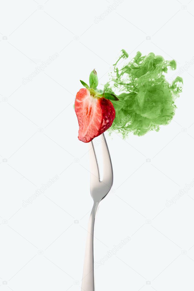 half of strawberry on fork and green ink isolated on white