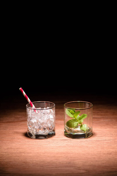 two glasses with ice cubes and mint for alcohol drinks on table