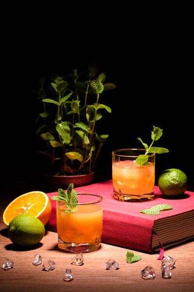 alcohol drinks with mint and fruits on pink book on table