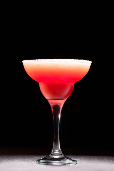 tasty red alcohol cocktail on wooden tabletop on black