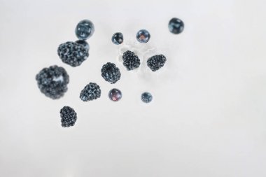 Juicy berries dropping into milk on white background clipart