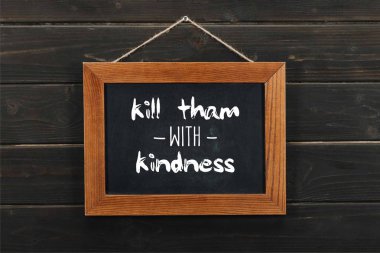 blackboard with kill tham with kindness inscription hanging on wooden wall  clipart