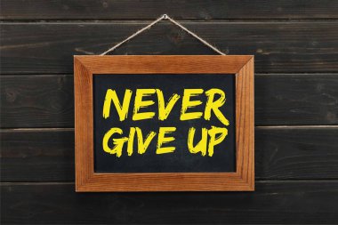 blackboard with inscription never give up hanging on wooden wall clipart
