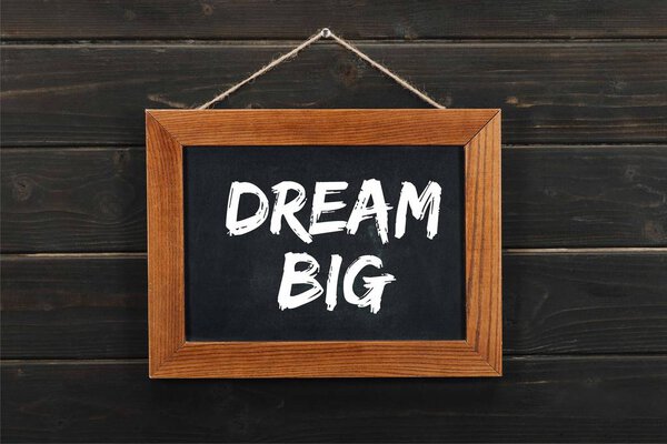 blackboard with dream big inscription hanging on wooden wall 