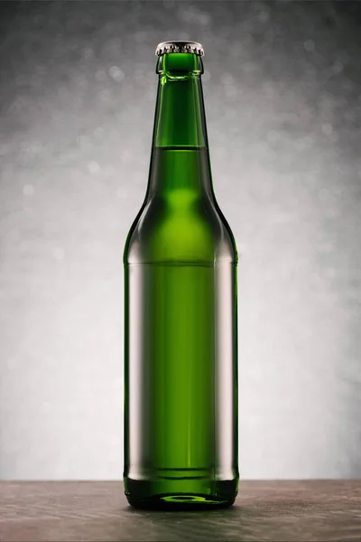 灰色背景下桌面上的啤酒瓶特写图 — 图库照片