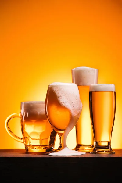 Vista Perto Canecas Arranjadas Cerveja Fria Com Espuma Fundo Laranja — Fotografia de Stock