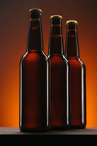 Close Van Gearrangeerde Flessen Bier Een Oranje Achtergrond — Gratis stockfoto