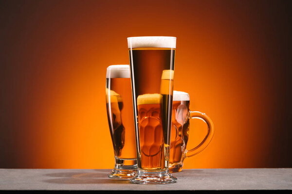 Крупный план расположения бокалов пива на оранжевом фоне
