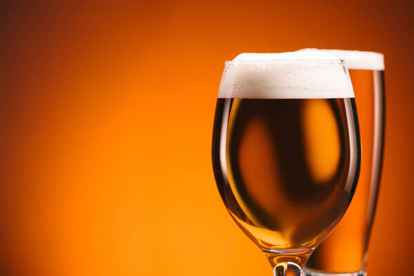 Крупный план расположения бокалов пива на оранжевом фоне
