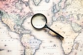 top view of magnifying glass on world map over atlantic ocean