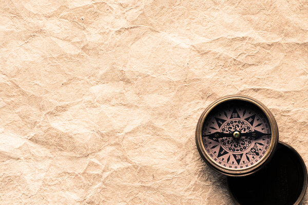 top view of navigation compass on blank crumpled paper