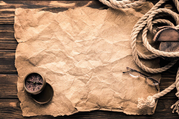 top view of blank crumpled paper with compass and rope on rustic wooden surface