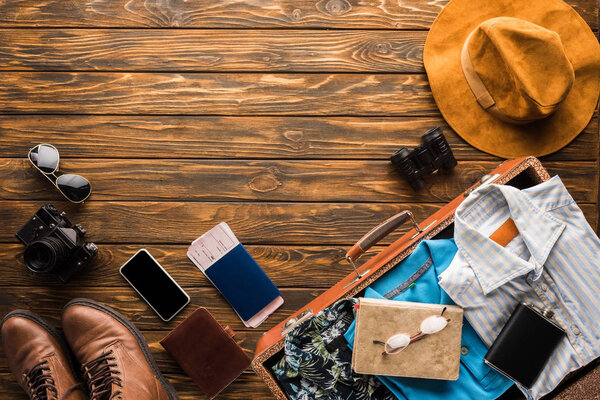 top view of vintage suitcase with baggage for travel on wooden tabletop