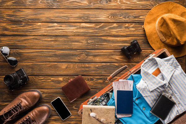 верхний вид ретро чемодана с багажом для путешествий по деревянной столешнице
