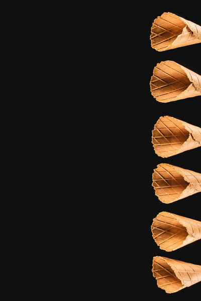 top view of row of ice cream cones isolated on black