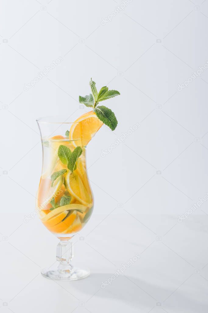 close up view of summer fresh cocktail with mint and pieces of citrus fruits isolated on white