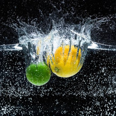 close up view of fresh lemons and limes in water isolated on black clipart