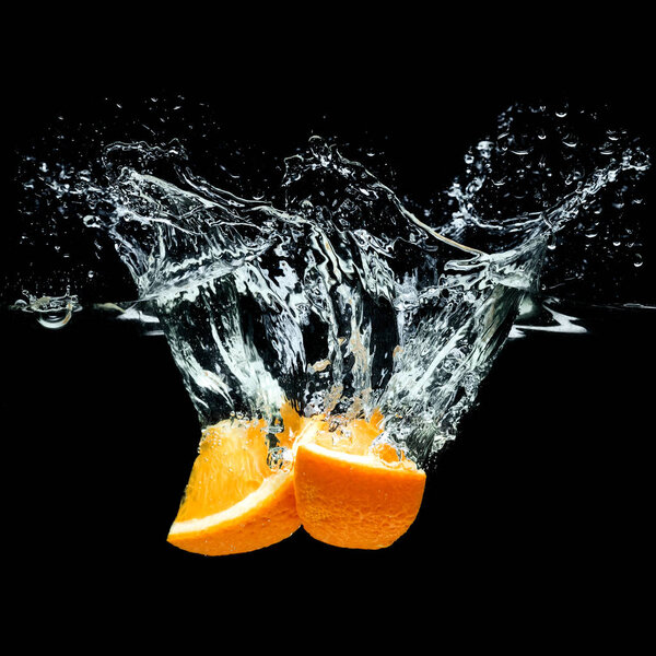 close up view of pieces of orange citrus fruit in water isolated on black