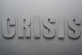 Draufsicht auf Papier geschnittenes Wort Krise auf grauem Hintergrund mit Schatten