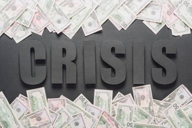 top view of word crisis near scattered dollar banknotes on black background with shadows clipart