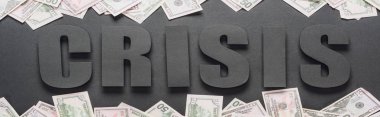 Kelime krizinin en üst görüntüsü, gölgeli, panoramik çekimli, siyah arkaplan üzerine dağınık dolar banknotları.