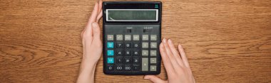 cropped view of female hands near calculator with one hundred thousand on display on wooden desk, panoramic shot  clipart