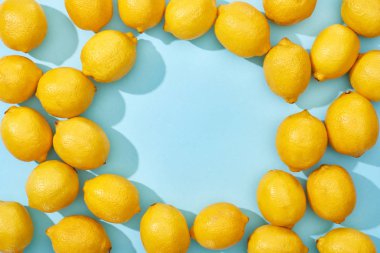 Mavi arkaplandaki olgun sarı limonların en üst görünümü gölgeler ve kopyalama alanı