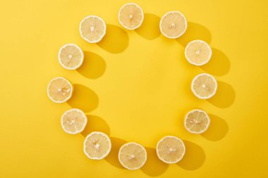 Olgunlaşmış limonlar, sarı arka planda tahta kesme tahtasıyla kesilmiş.