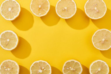 Sarı arkaplanda kare çerçeveye yerleştirilmiş olgun limonların üst görünümü