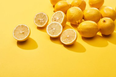 ripe cut and whole lemons on yellow background clipart