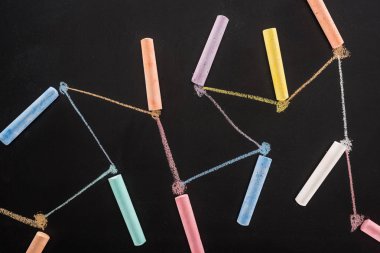 top view of colorful chalk on black surface with connected drawn lines, connection and communication concept clipart