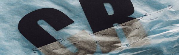 panoramic shot of black c and r etters immersed in paper symbolizing water on grey paper background