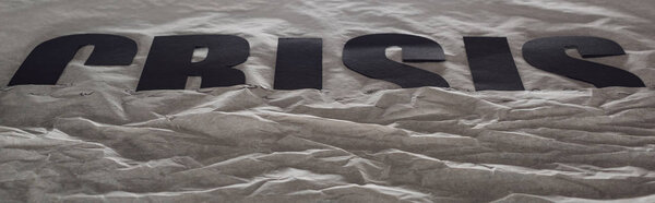 panoramic shot of black word crisis immersed in grey paper symbolizing water