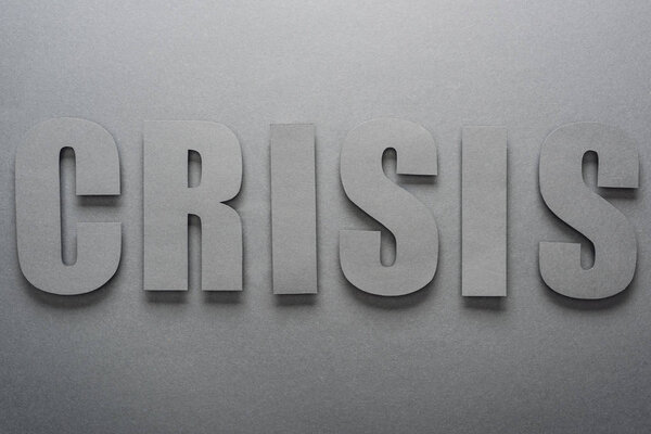 top view of paper cut word crisis on grey background with shadows