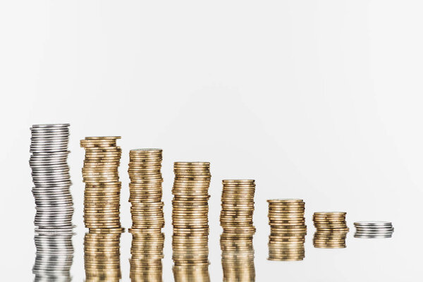stacks of silver and golden coins on surface with reflection isolated on white