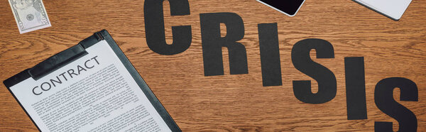 top view of word crisis, contract on clipboard and dollar banknote on wooden desk, panoramic shot