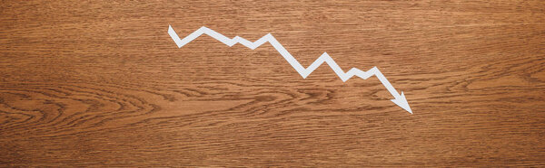 top view of white paper cut recession arrow on wooden desk, panoramic shot