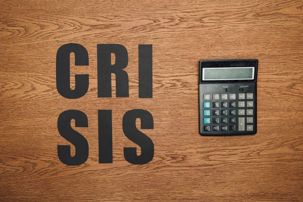 Top View Black Paper Cut Word Crisis Calculator Wooden Desk — Stock Photo, Image