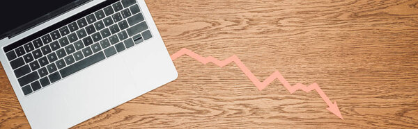 top view of laptop and recession arrow on wooden desk, panoramic shot 