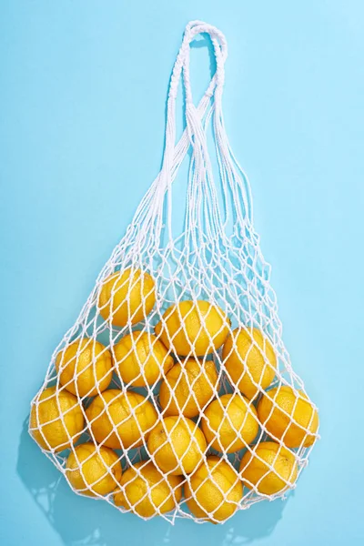 Mavi Arkaplanda Sicim Torbasında Olgun Sarı Limonların Üst Görünümü — Stok fotoğraf
