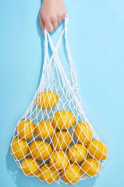 Обрезанный Вид Женщины Держащей Спелые Желтые Лимоны Струнном Мешке Синем — стоковое фото