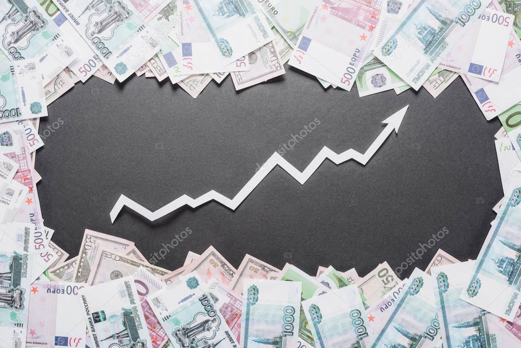 white paper cut increase arrow in frame of dollar, euro and ruble banknotes on black background