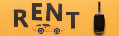 top view of paper cut car, key and black rent lettering on orange background, panoramic shot