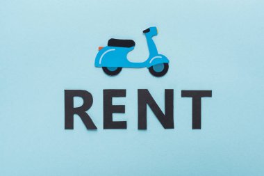 Kağıt kesim scooter ve mavi arkaplanda siyah kira harflerinin üst görünümü